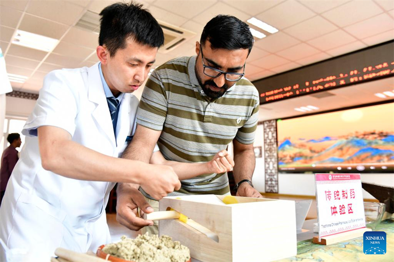 Un étudiant international de l'Université de Qingdao (à droite) apprend l'art de fabriquer des batonnets de moxa utilisés en moxibustion dans un h?pital de médecine traditionnelle chinoise (MTC) à Qingdao, dans la province du Shandong (est de la Chine), le 18 juin 2024. (Guo Xulei / Xinhua)