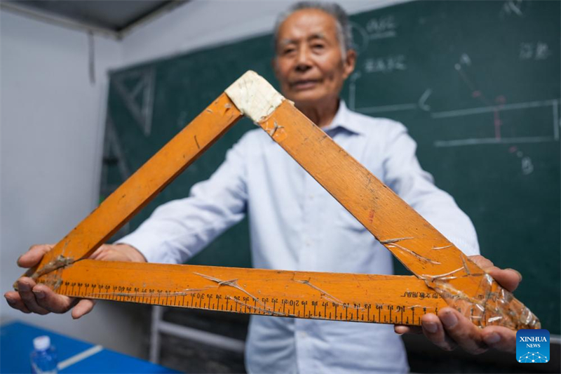 Ma Rusong montre la règle triangulaire qu'il a utilisée tout au long de sa carrière d'enseignant chez lui, dans le village de Shenyang de la ville de Taizhou, dans la province du Jiangsu (est de la Chine), le 30 juillet 2024. (Li Bo / Xinhua)